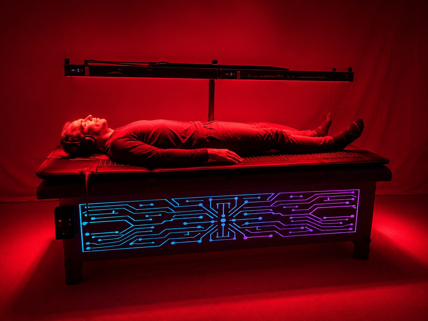 Side view of a person lying on the Vibro Vessel with headphones on